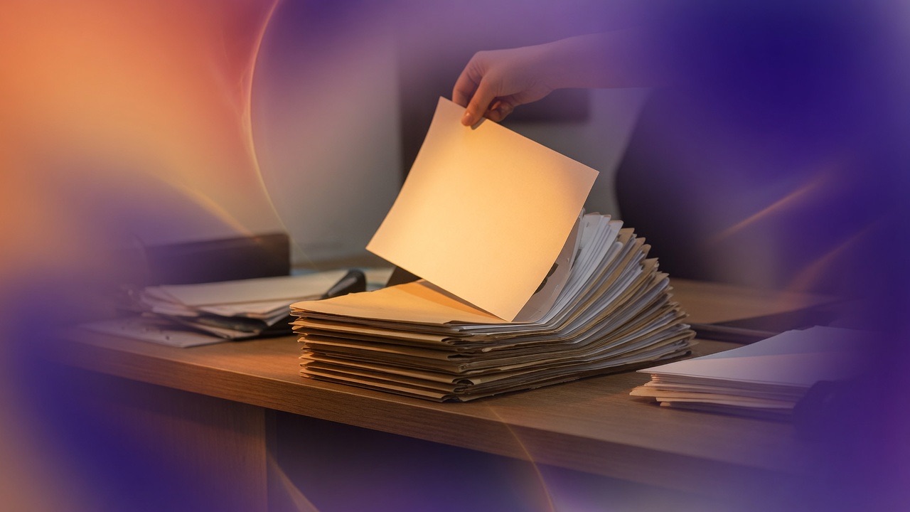 A hand lifting a blank page from a tall stack of folders