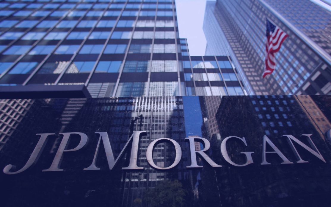 JPMorgan lettering in front of glass office towers, with an American flag.