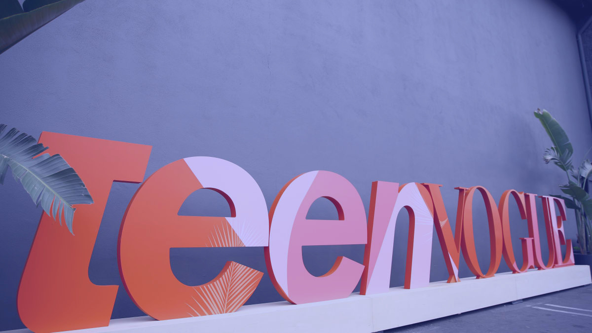 Large Teen Vogue letters on a white plinth against a blue wall.